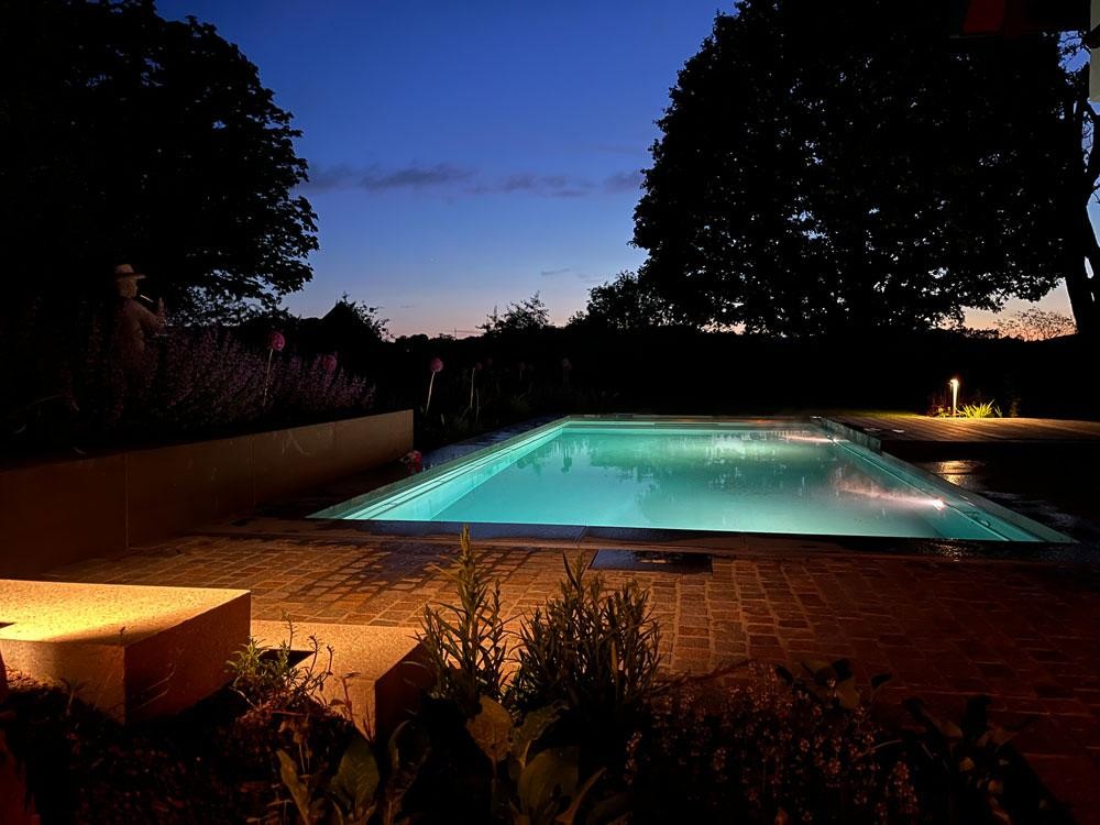 Beleuchteter Naturpool am Abend mit Gartenstimmung