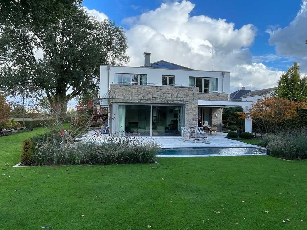 Biopool vor moderner Villa mit Terrasse und gepflegtem Garten