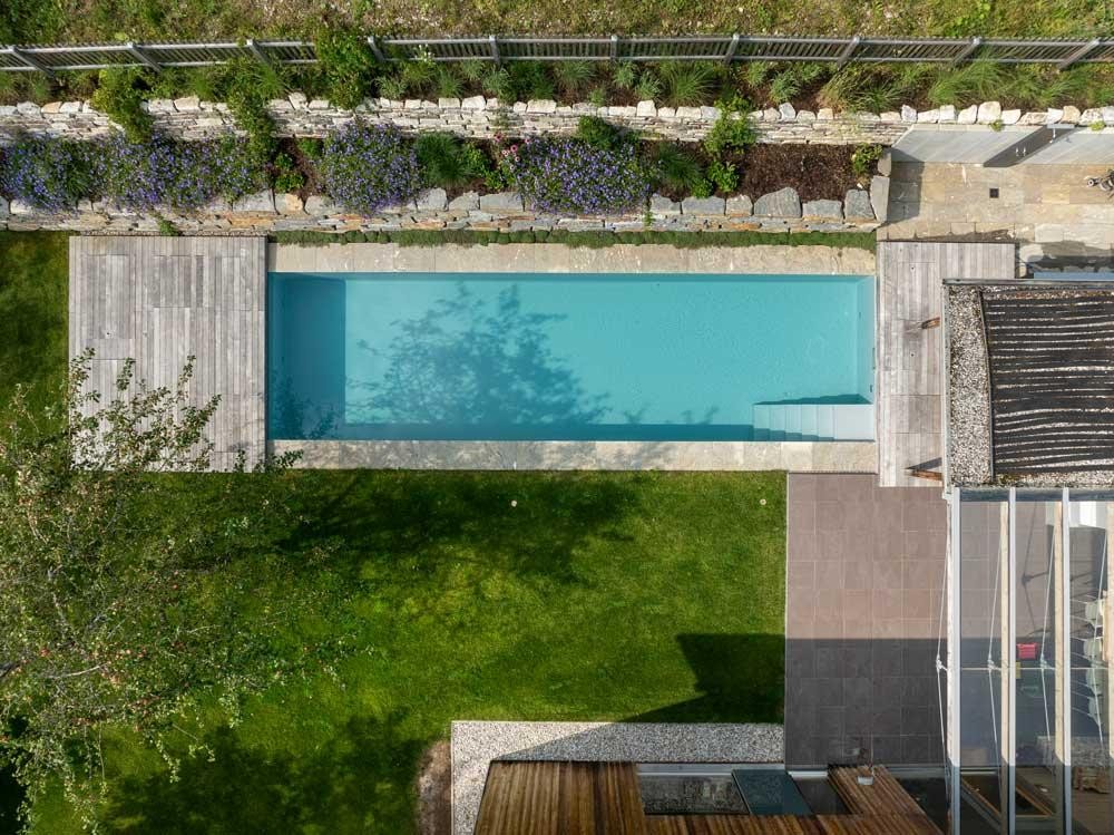 Biopool von oben mit Terrasse, Rasenfläche und Natursteinmauer