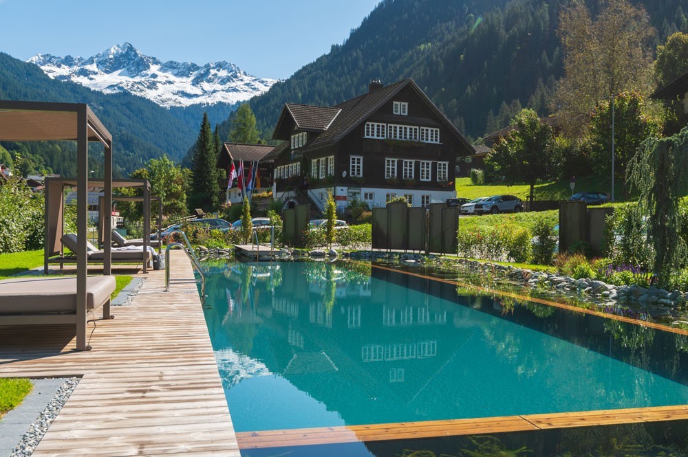 Hotelpool mit Bergblick vor Alpenhotel und Holzdeck