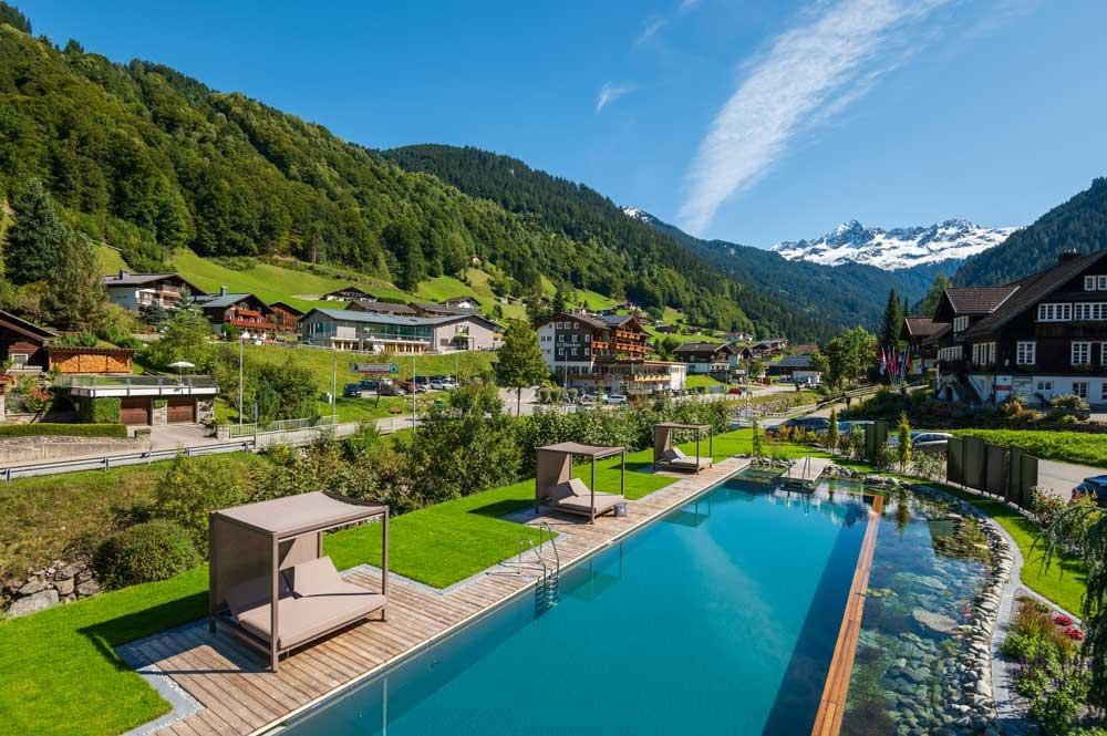 Luftaufnahme von Hotelpool im Alpendorf mit Bergkulisse
