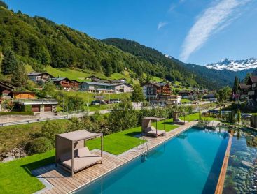 Luftaufnahme von Hotelpool im Alpendorf mit Bergkulisse