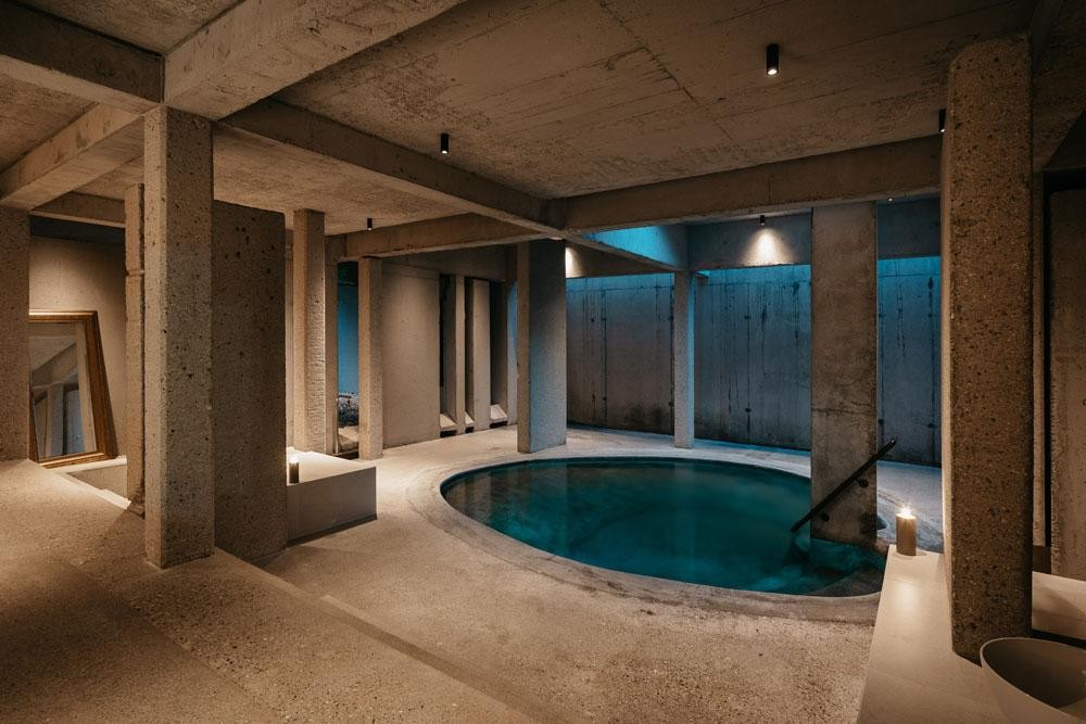 Runder Innenpool mit Betonarchitektur und stimmungsvoller Beleuchtung