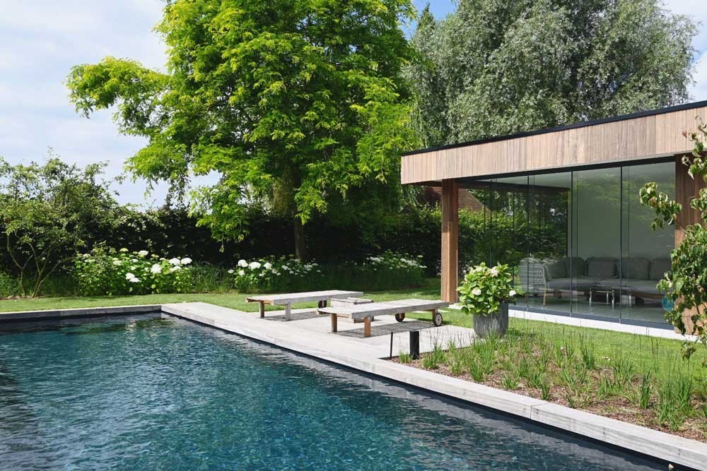 Naturpool mit modernem Poolhaus in einem gepflegten Garten mit Terrasse
