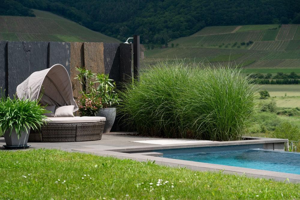 Naturpool mit Loungeplatz in Hanglage und weitem Landschaftsblick