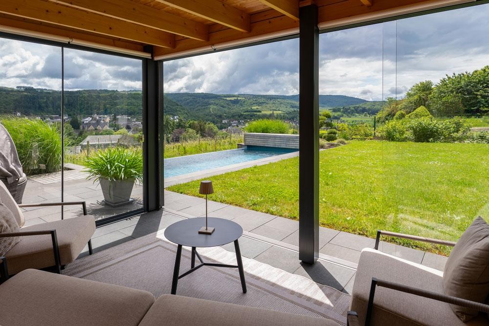 Blick aus dem Wohnraum auf Naturpool und weite Landschaft