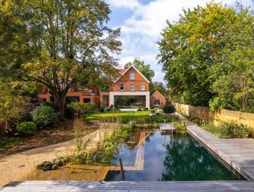 Naturpool mit Holzdeck und Gartenhaus im naturnahen Garten