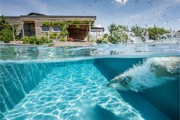 Chlorfreies kristallklares Wasser in einem Biotop Naturpool mit Unterwasserblick und schwimmender Person im Garten