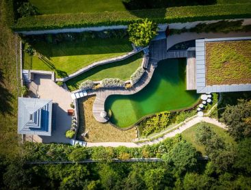 Biotop Naturpool von oben mit Holzdeck Gruendach und Garten