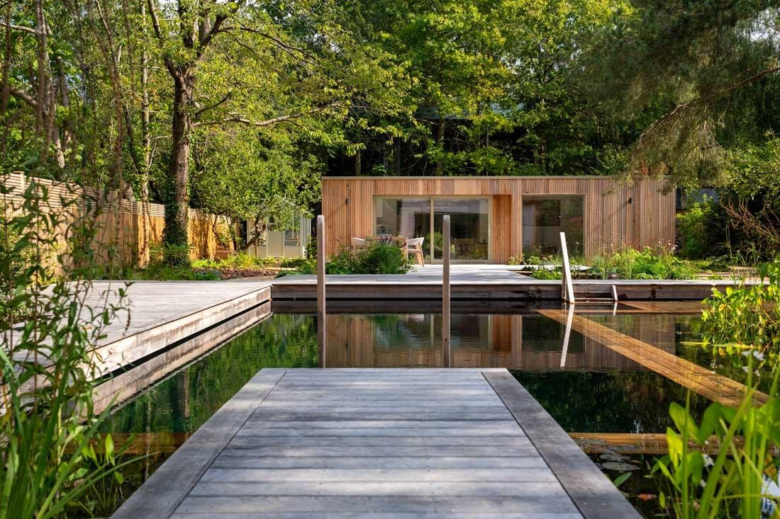 Naturpool mit Regenerationszone und Holzsteg im naturnahen Garten