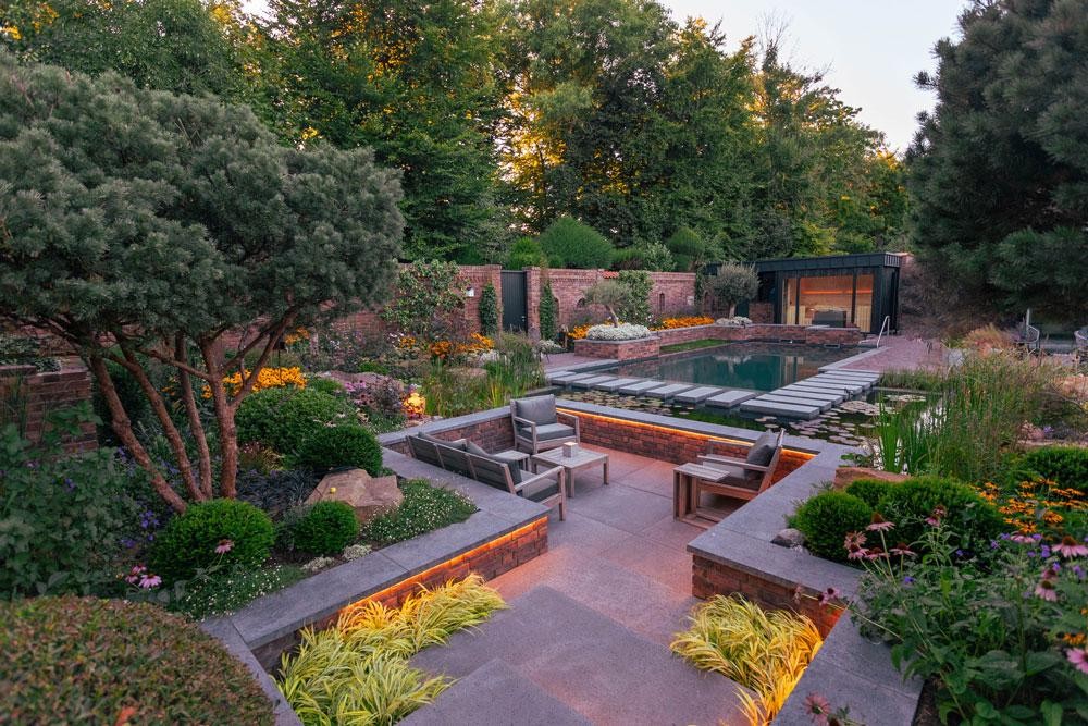 Naturpool mit Sitzplatz und stimmungsvoller Gartenbeleuchtung
