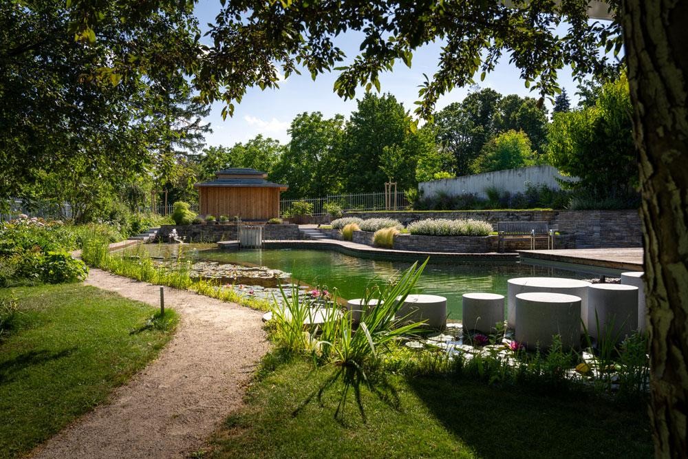 Biotop Schwimmteich mit Seerosen Trittsteinen und Gartenanlage
