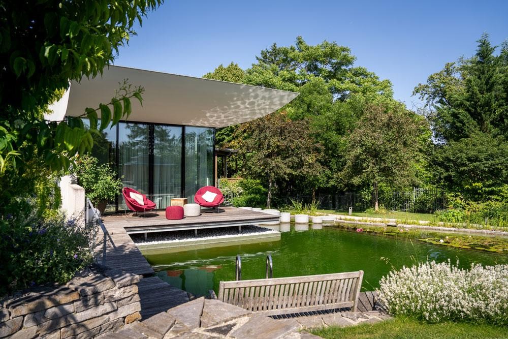 Biotop Schwimmteich an moderner Terrasse mit Holzdeck und Sitzplatz