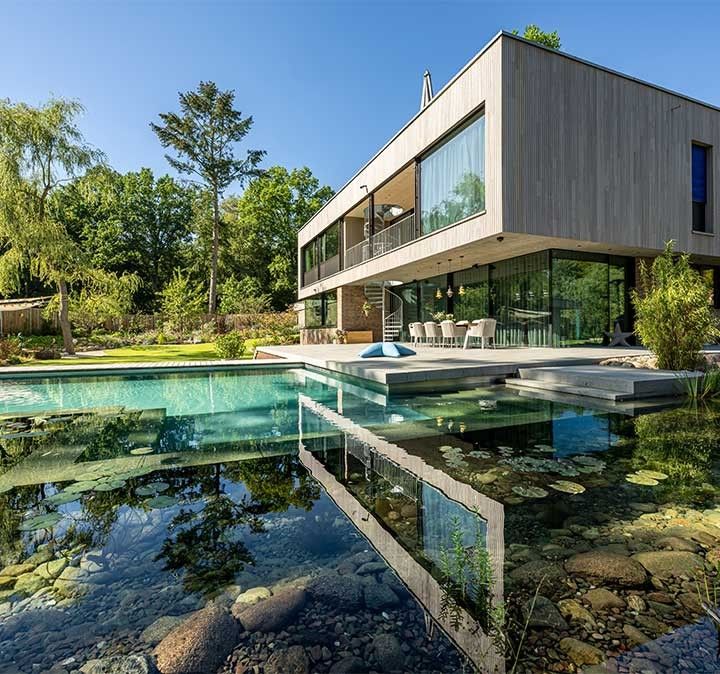 Moderner Swimming Pond von Biotop mit eckigen Designelementen in Steineinfassung