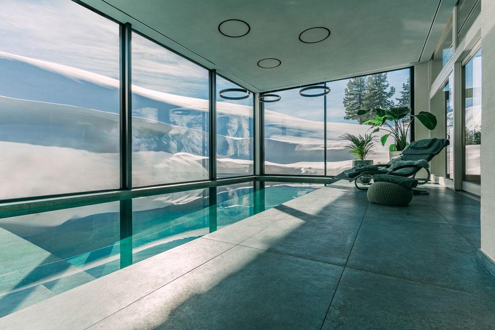 Heller Indoor Living Pool mit Glasfront und verschneiter Landschaft