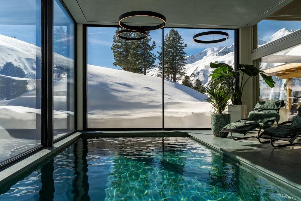 Indoor Living Pool mit Bergblick und Liegen im Wellnessraum