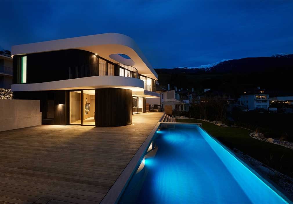 Moderne Architektur mit beleuchtetem Naturpool bei Nacht in Italien