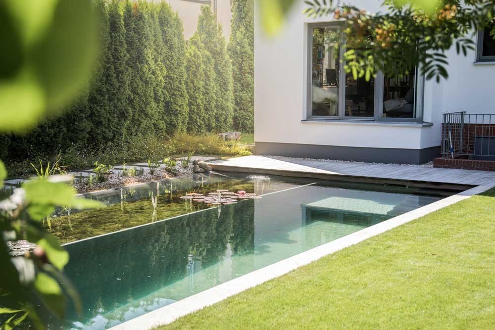 Moderner Schwimmteich am Haus mit klaren Linien und Regenerationszone im Garten
