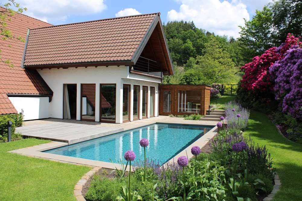 Naturpool am Haus mit Holzdeck und bluehendem Garten