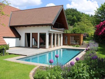 Naturpool am Haus mit Holzdeck und bluehendem Garten
