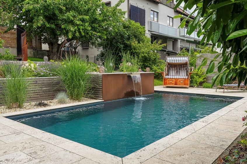 Moderner Gartenpool mit Wasser umgeben von Pflanzen und Wasserfall Element