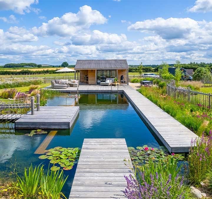 Naturpool mit angrenzender Holzterrasse und zusaetzlichen Inselelementen