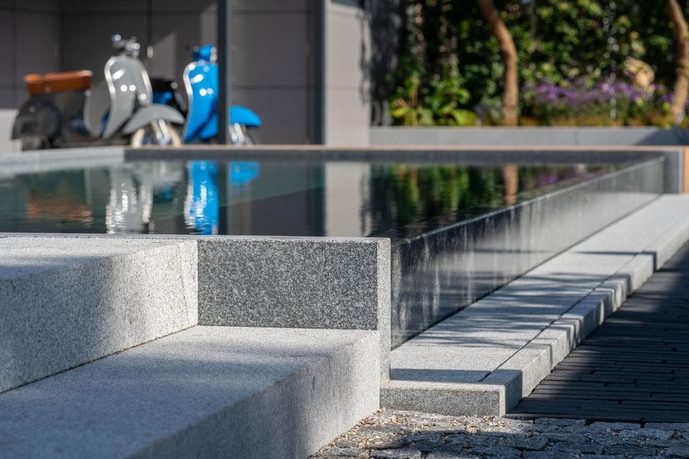Detailaufnahme eines Naturpools mit Kusser Granitkante und Stufen