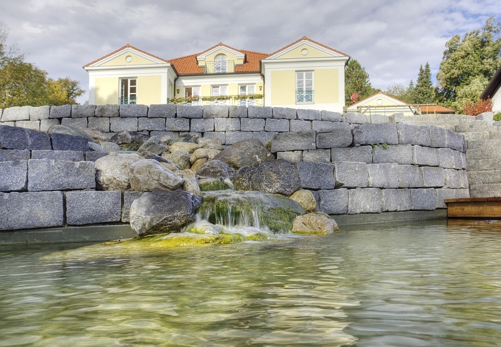 Schwimmteich in Deutschland mit Natursteinmauern und Wasserfall