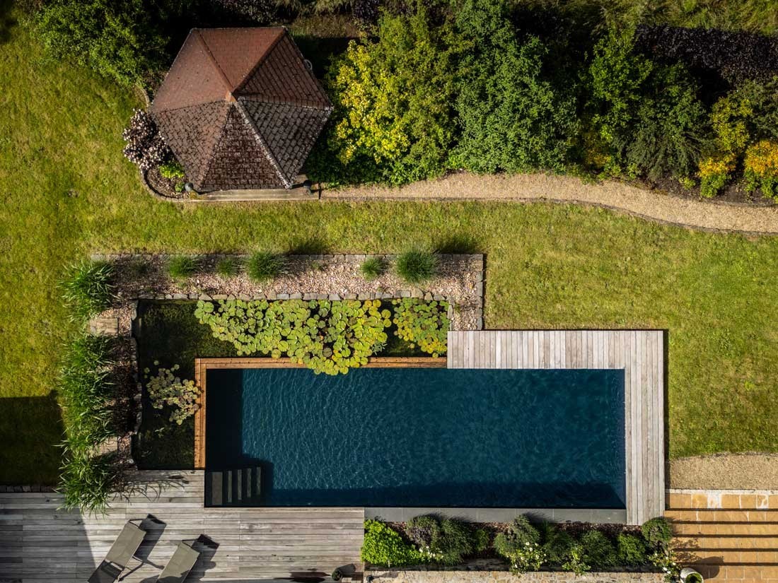 Schwimmteich von oben mit Seerosen und Holzdeck