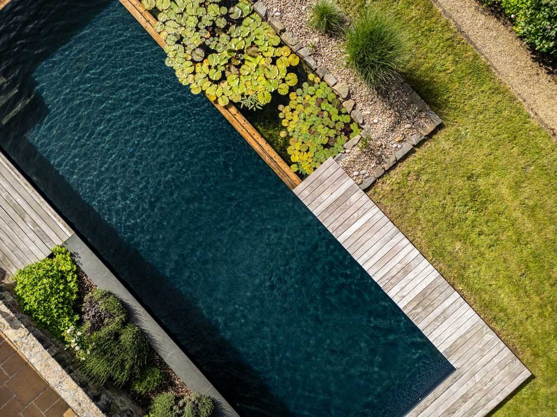Schwimmteich mit Holzdeck in weitläufiger Gartenlandschaft