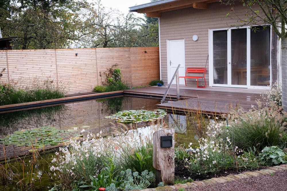 Schwimmteich mit Holzdeck und naturnahem Garten