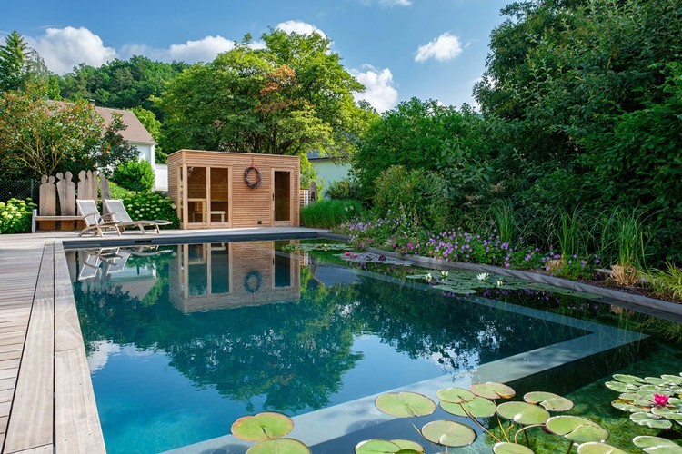 Ein großer Schwimmbteich mit Seerosen und einer Sauna im Garten