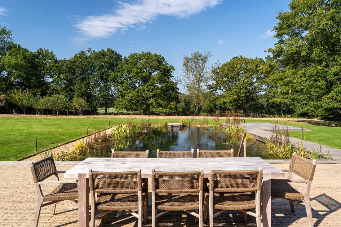 Gartenmoebel auf einer Terrasse im eigenen Garten angrenzend an einem Schwimmteich